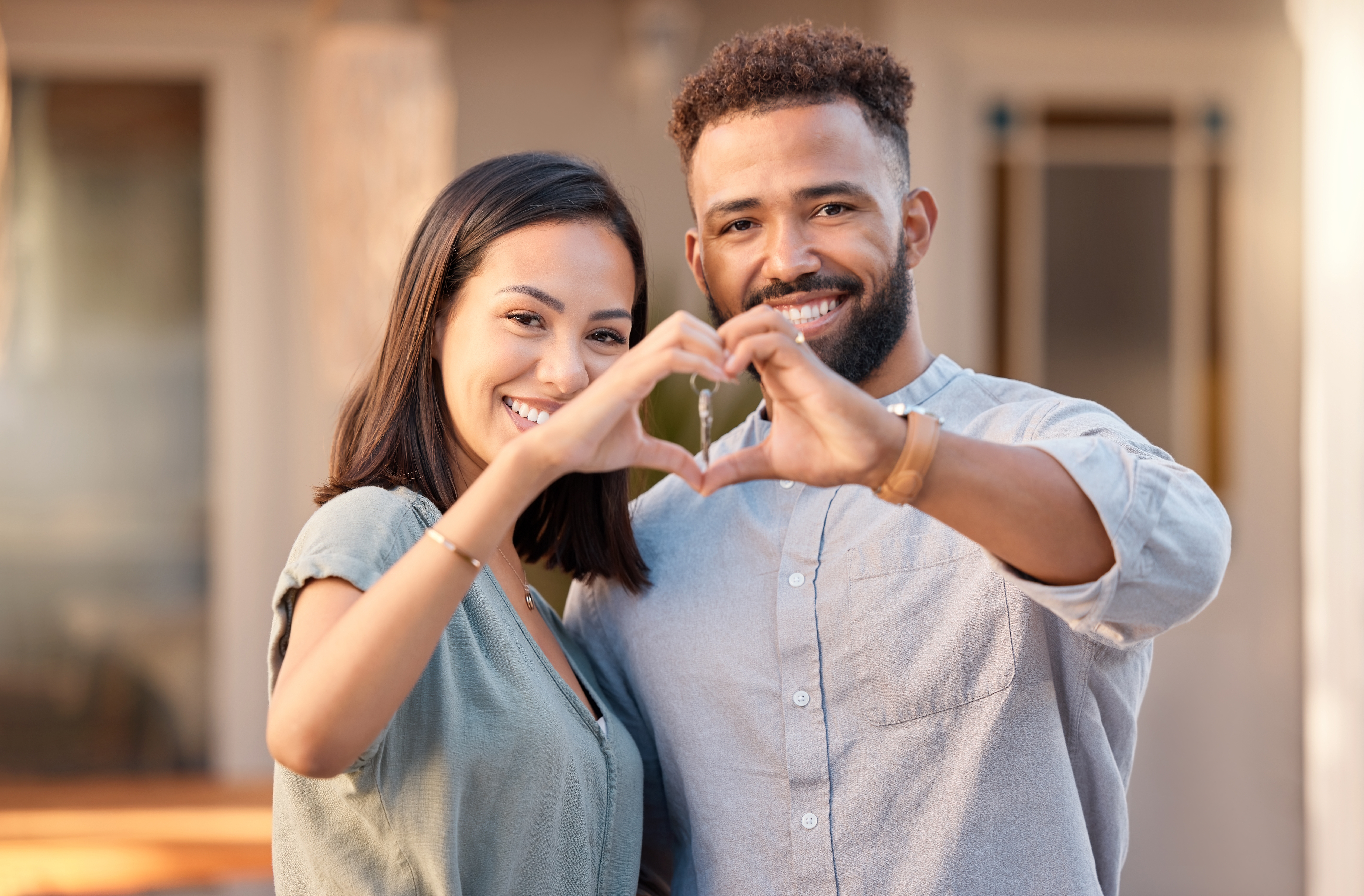 Homeowners in front of their new home checking to see if they need home roof repairs, a home roof replacement, or a new roof installation.